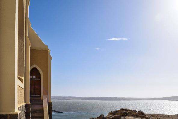 Kirche von Lüderitz. An der Tür hängt ein Zettel, auf dem auf deutsch steht: Gottesdienst um 18:00